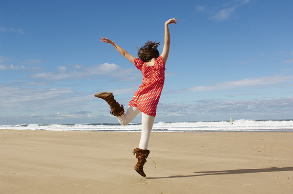 Teenage girl (16-17) dancing on beach, rear view